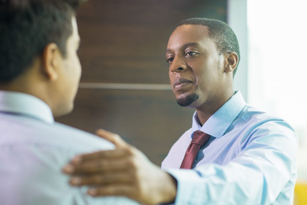 Counsellor placing a reassuring hand on a client's shoulder