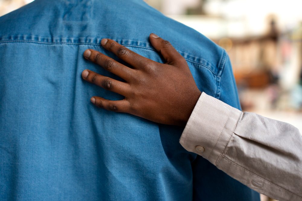 A supportive hand resting on a person's back