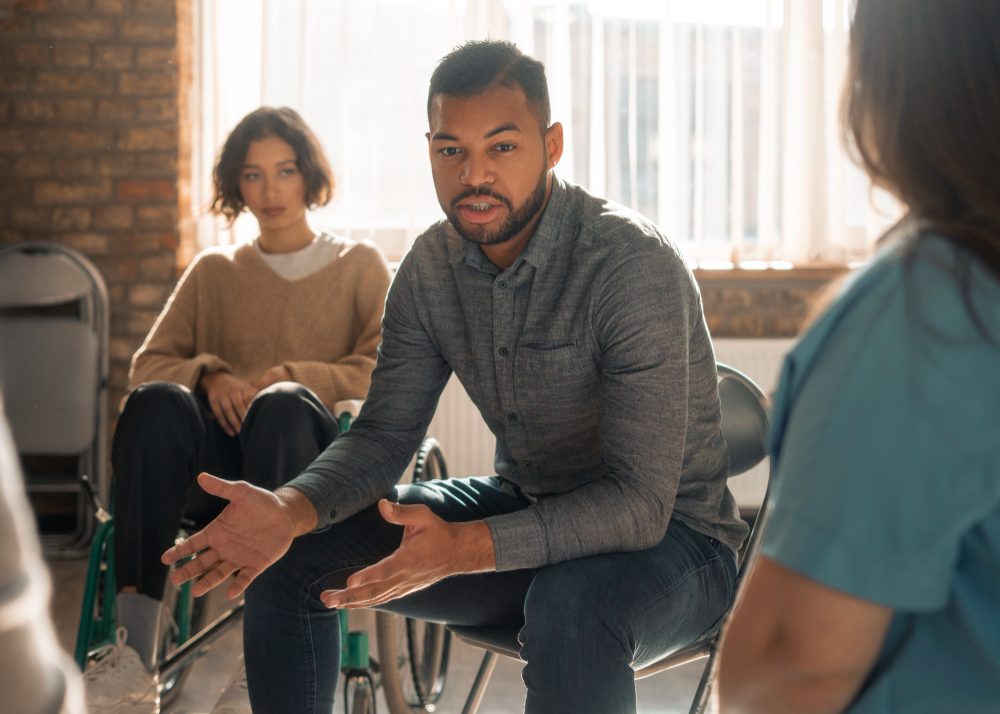 Man speaking to a recovery support group seated in a circle